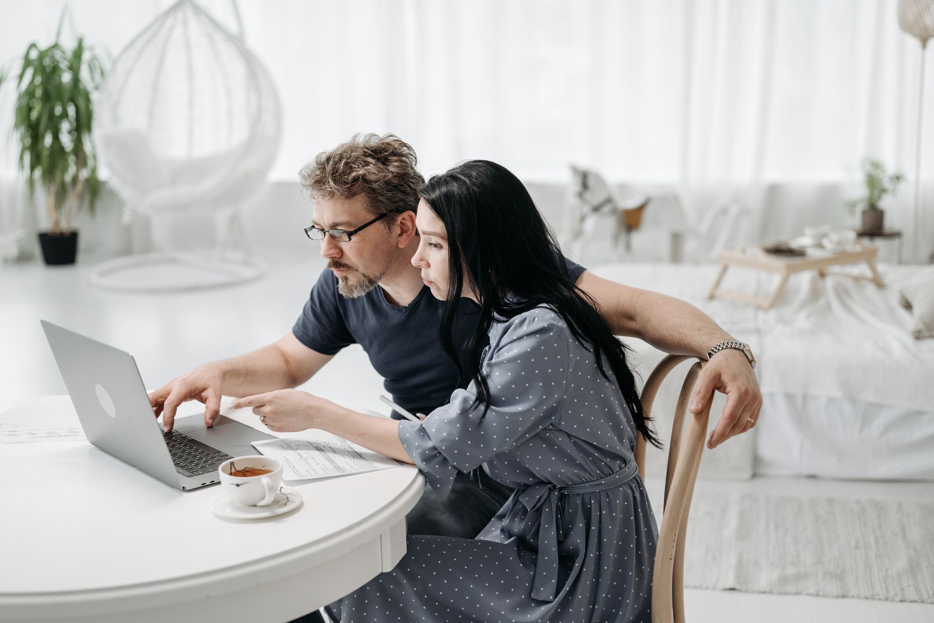 Man en vrouw zitten samen aan tafel achter een laptop met koffie