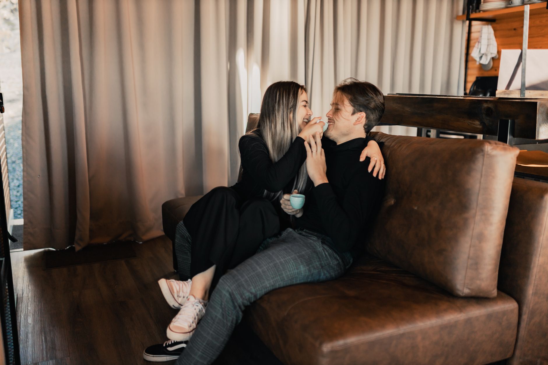 Man en vrouw lachen samen met een kop koffie op de bank